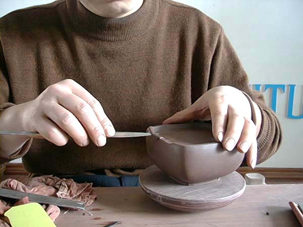 22、以旁皮刀切割出圈足以外不要的泥片，僅留下未切掉的，形成四個壺底角落的圈足。