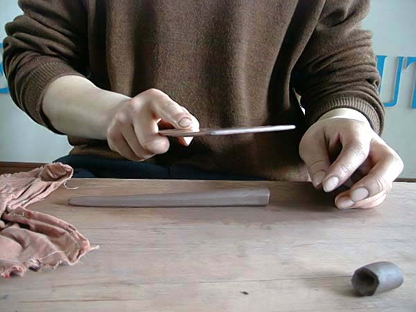 27、以木拍子碾滾出頭大尾小的圓泥條，再用木拍子拍出製作壺把需要的方形泥條。