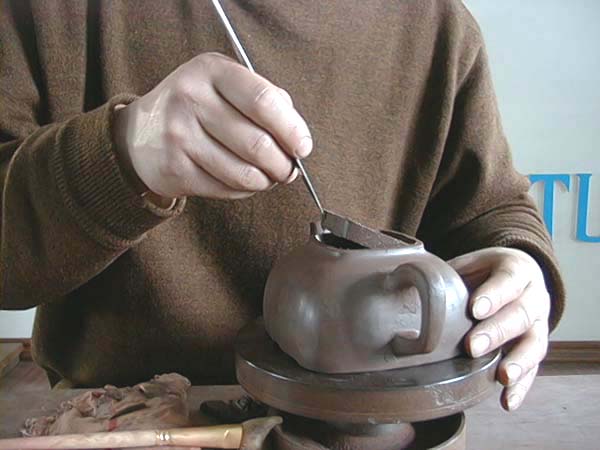 41、以旁皮刀按所需大小開出壺口，再將切下之泥片去掉，然後以蓋子來回套整，並修飾壺口至自然工整，與壺蓋套合緊密平整無縫始可。
